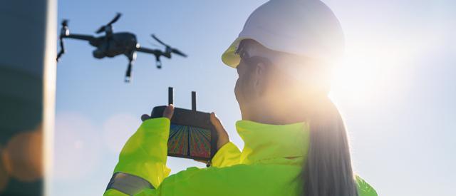 two people flying a drone at sunset.